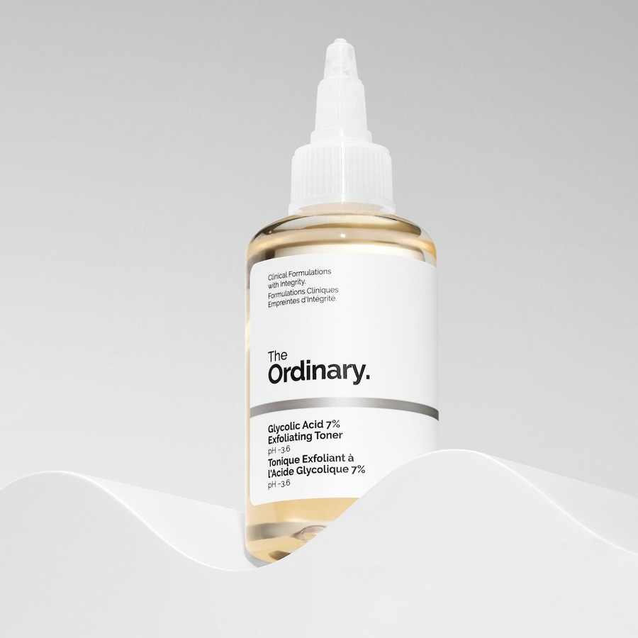 The Ordinary Glycolic Acid 7% Exfoliating Toner elegant gefotografeerd op een golvende ondergrond, met zachte belichting.